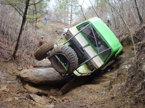 1978 Ford Bronco - An off-road vehicle is seen tipped on its side while navigating a challenging rocky terrain.