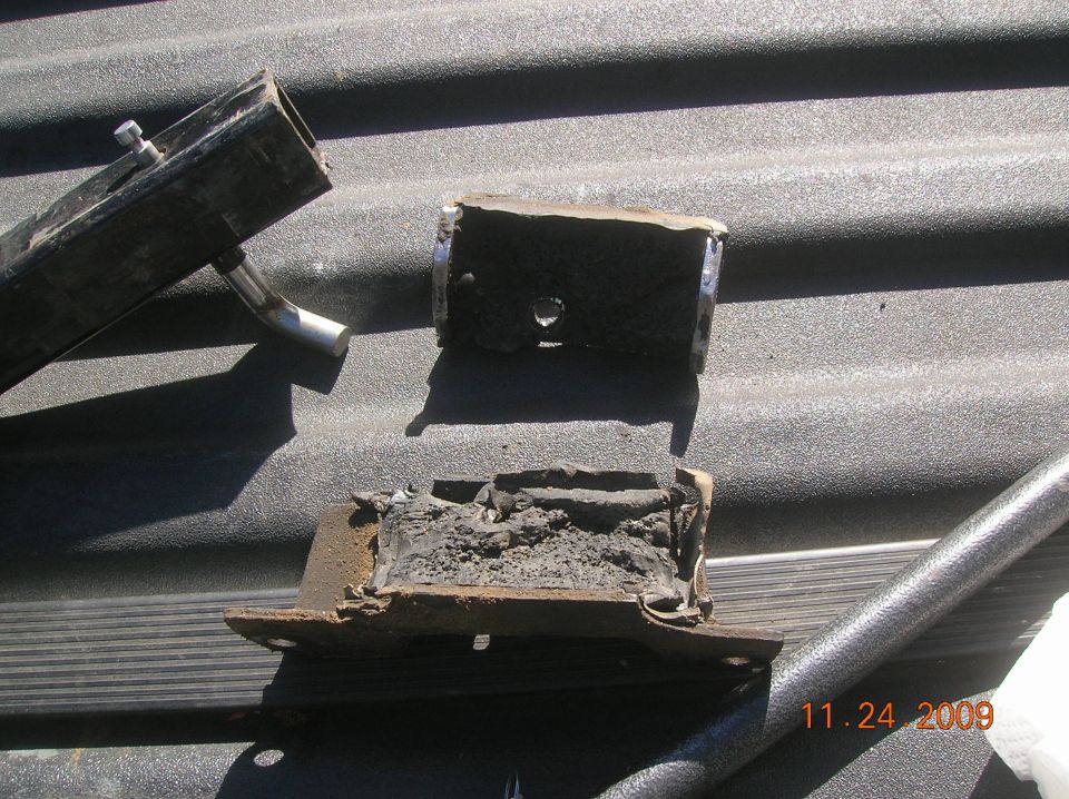 Two damaged rubber and metal vehicle mounts on a textured surface