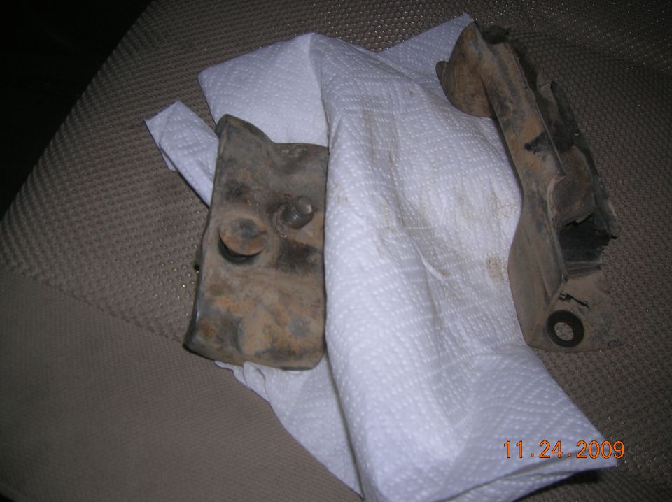 two rusty metal parts on paper towels, possibly car parts