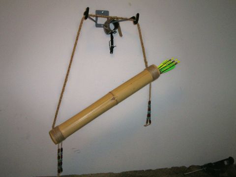 1993 Ford Bronco - A handmade bamboo quiver hanging from a wall hook by a braided cord sling on a plain white wall, loaded with arrows whose neon green and ye…