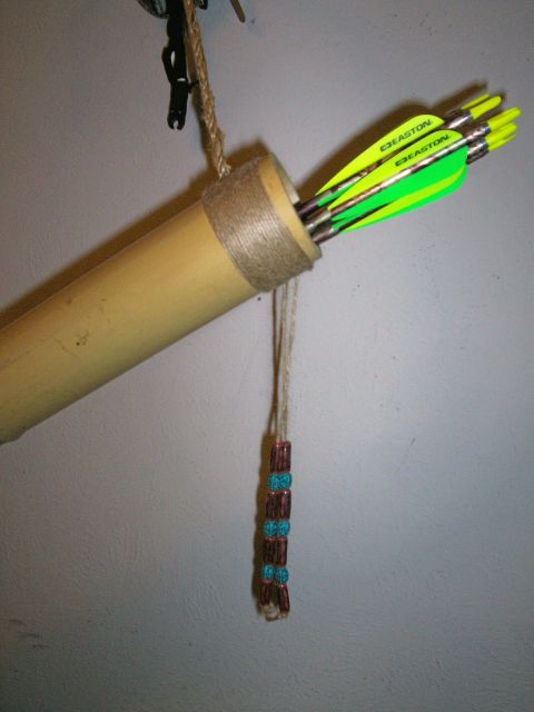 1993 Ford Bronco - A handmade bamboo quiver hanging against a white textured wall, its mouth wrapped in twine and decorated with a beaded turquoise-and-red da…