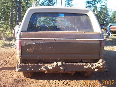 1994 Ford Explorer - This muddy SUV is seen from the rear, with another vehicle and people visible in the background.