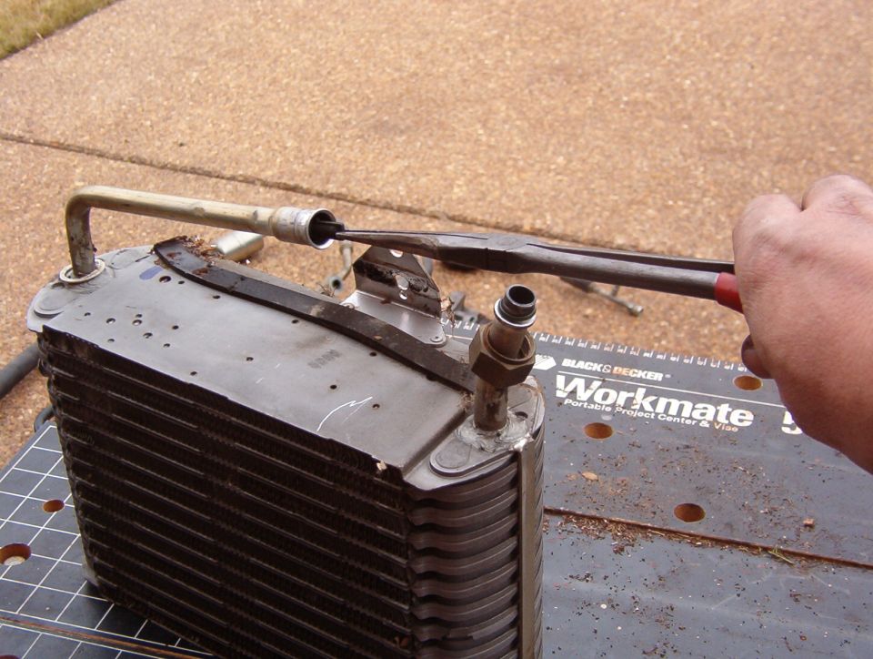 After recovering the refrigerant (using the proper equipment according to applicable laws), remove the orifice tube from the evaporator core inlet.  This can be quite difficult, especially if it's clogged - the pressure of the system trying to work commonly forces the orifice beyond the detents in the tubing.  There are [url=https://www.amazon.com/dp/B000O809FY]special tools available to extract the orifice[/url], and there are [url=https://www.ebay.com/itm/182166858842]replacement tubes[/url] available so that the impacted one can simply be cut off with the orifice still inside.