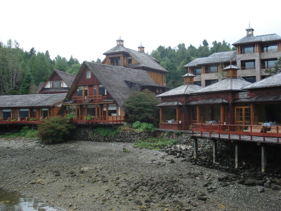 Wooden buildings with balconies and large roofs stand on a rocky shore