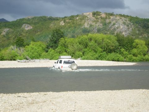1986 Ford Bronco - A white 1986 Ford Bronco navigates a river crossing, its off-road capability.