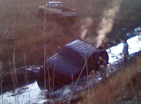 1992 Ford F-350 - A truck is stuck in the mud, with another truck in the background and steam rising from the stuck vehicle.