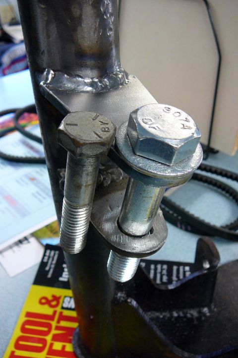 1984 Ford Bronco - Close-up of a metal bracket with bolts, showing manufacturing details and markings.