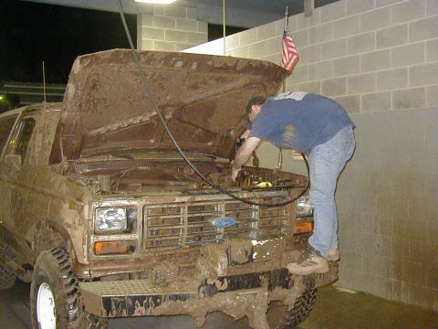 1994 Ford Explorer - Mud-covered Ford Bronco with hood open, a man works on the engine inside a garage.