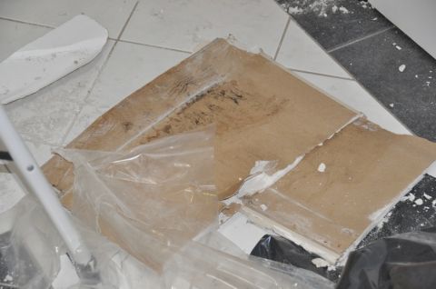 1996 Ford Bronco - Construction debris is piled on a tiled floor, with some pieces of drywall and cardboard visible.