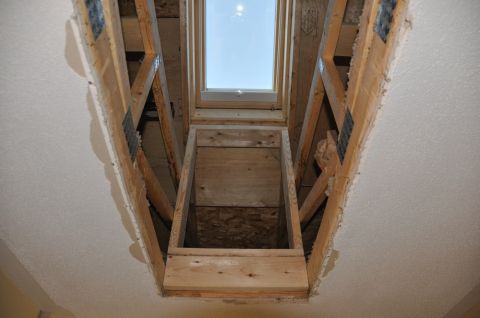 1996 Ford Bronco - Construction of a skylight tunnel reveals unfinished wooden framing and a view of the sky above.