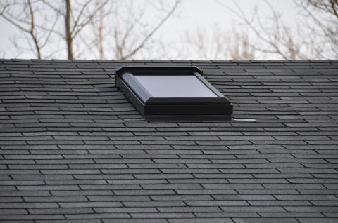1996 Ford Bronco - A skylight is installed on a residential roof, with a cloudy sky and trees visible above.