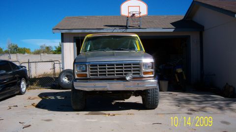 1981 Ford Bronco - This lifted Ford F-Series truck is parked in front of a garage with a basketball hoop above.