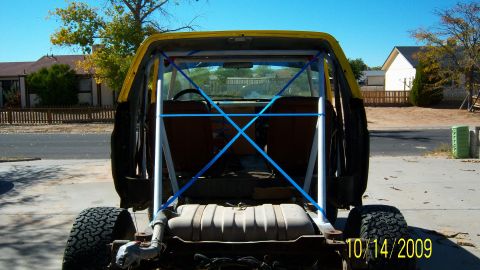 1981 Ford Bronco - This yellow SUV, likely from the early 1980s, is viewed from the rear, showing a custom roll cage and fuel tank.