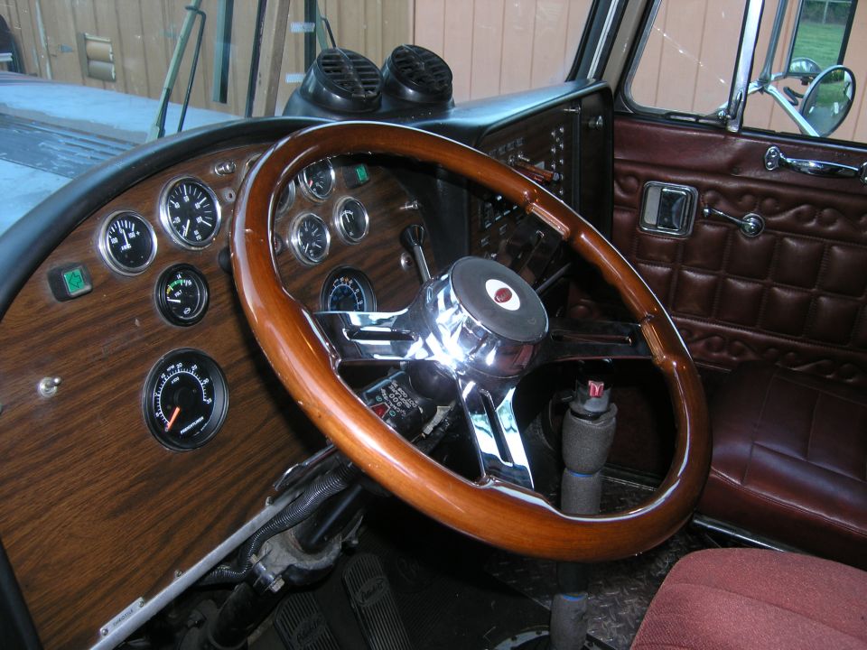 Custom wood-rimmed steering wheel and dash with multiple round gauges in a vehicle