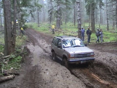 1994 Ford Explorer - Ford Explorer tackles a challenging muddy off-road course in a wooded area.