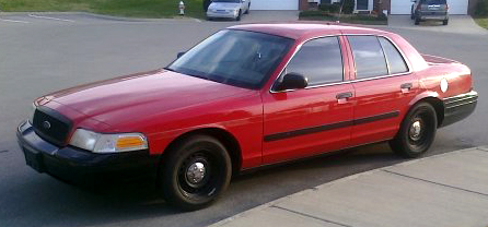 2002 Ford Crown Victoria - A red 2002 Ford Crown Victoria is parked curbside on a sunny day.