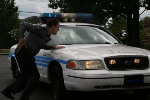 2000 Ford Crown Victoria - A police officer leans on the hood of a white 2000 Ford Crown Victoria patrol car.