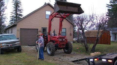 2000 Chevrolet Tahoe - A red tractor with a front loader is parked in a driveway next to a silver SUV.