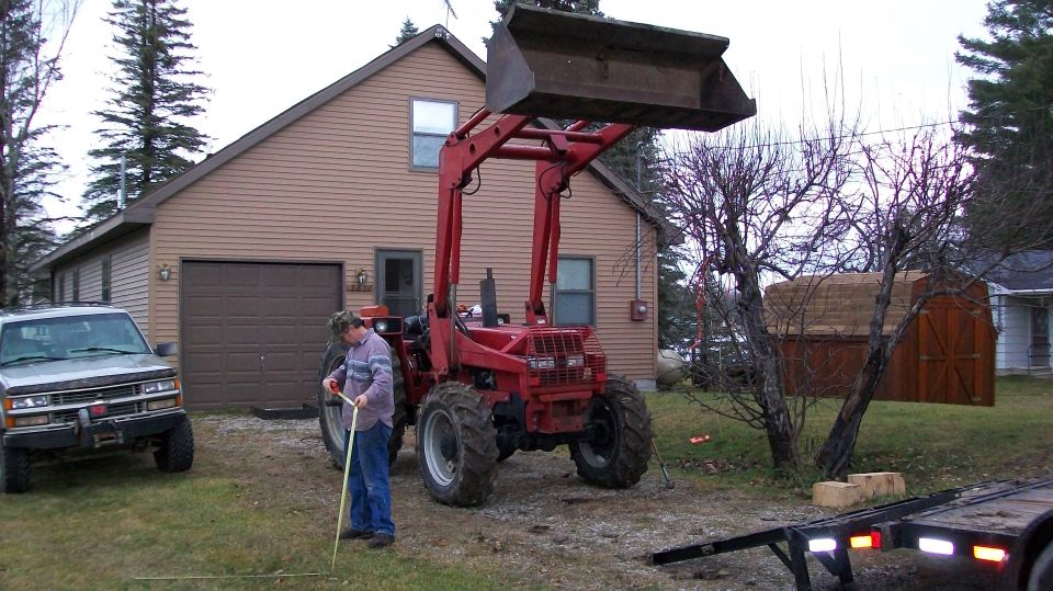 Red tractor with front loader parked in driveway next to a silver SUV