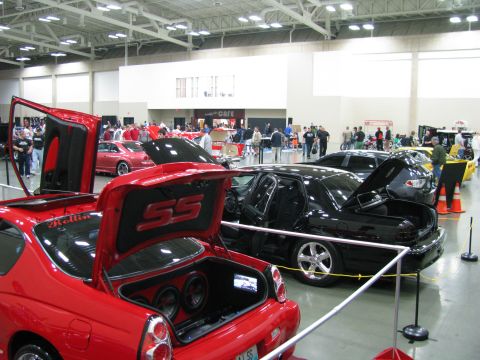 2003 Mercury Marauder - A red car with its trunk open, displaying custom audio equipment and 'SS' badging, is parked indoors at a car show.