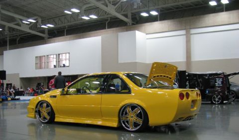 2003 Mercury Marauder - Custom yellow coupe with large aftermarket wheels and an open trunk at a car show.