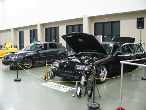 2003 Mercury Marauder - Two cars are displayed indoors, one with its hood open, at a car show.