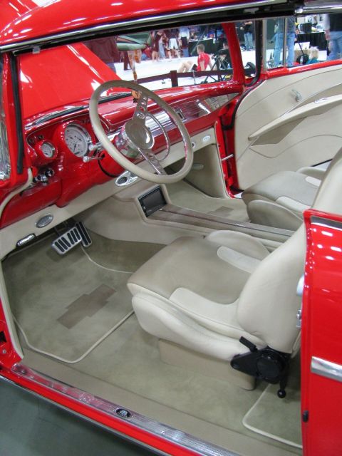 2003 Mercury Marauder - The interior of a red car features tan upholstery, a custom steering wheel, and a Chevrolet floor mat.