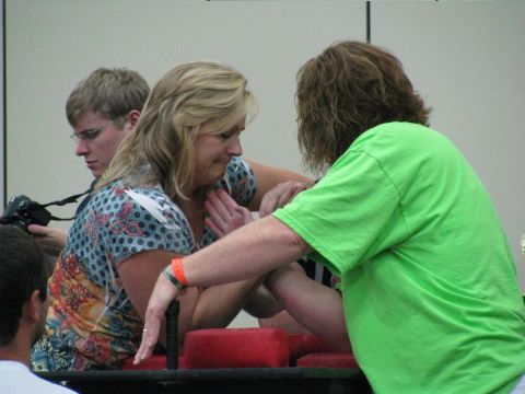 2003 Mercury Marauder - A man photographs two women engaged in an arm wrestling match at an event.