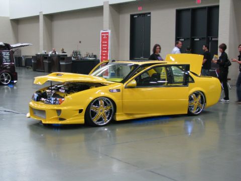 2003 Mercury Marauder - A bright yellow custom sedan is displayed with its hood and trunk open, revealing the engine and interior.