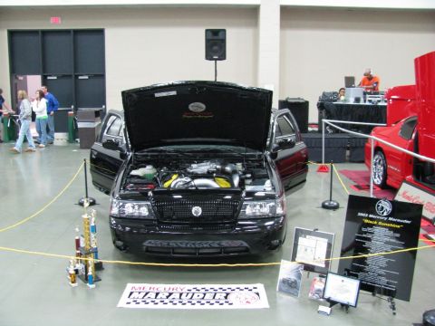 2003 Mercury Marauder - A black 2003 Mercury Marauder is displayed with its hood open, surrounded by trophies and informational signs.