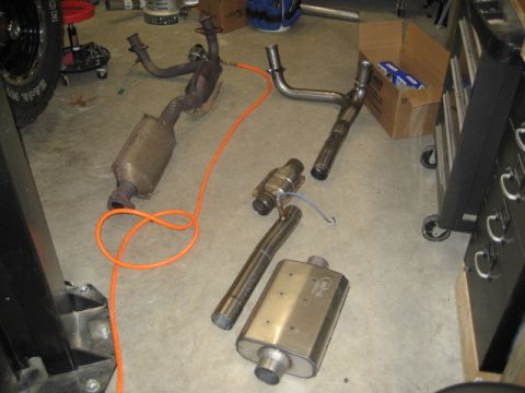 1996 Ford Bronco - Various exhaust system components are spread across a garage floor.