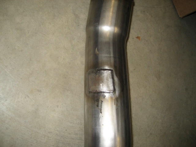 Close-up of a metal exhaust pipe showing a welded repair patch
