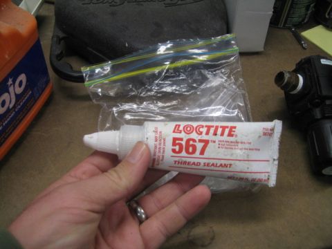 1996 Ford Bronco - A hand holds a tube of Loctite 567 thread sealant, with a plastic bag and other items in the background.