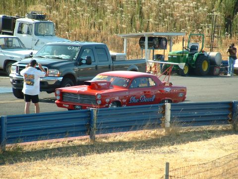 1991 Ford Bronco - A red drag car with "She Devil" text is seen at a race track with other vehicles.