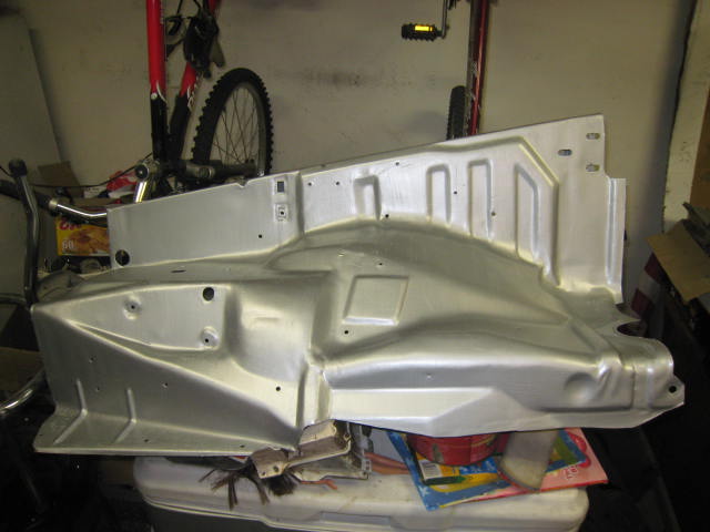 Silver-painted stamped sheet metal body panel resting on a cooler in a garage with a bicycle behind it