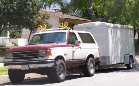 1990 Ford Bronco - This Ford Bronco is equipped with off-road tires and is towing a large white cargo trailer.