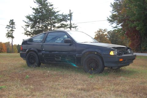 1996 Ford Probe - A black hatchback sits in a grassy field with its hood open and front grille removed.