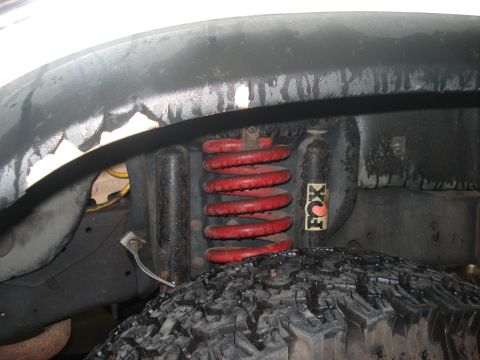 1986 Ford Bronco - The vehicle's suspension system features a red coil spring and a FOX shock absorber, indicating aftermarket modifications.