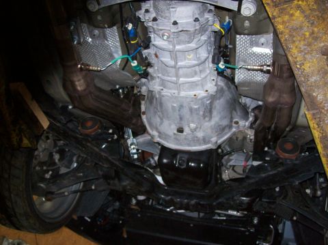 2007 Ford Mustang - Underside view of a vehicle's transmission, exhaust headers, and suspension components, showing the drivetrain and exhaust system.