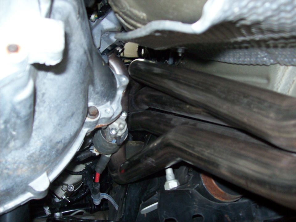 Close-up of shiny exhaust headers and engine parts under a vehicle