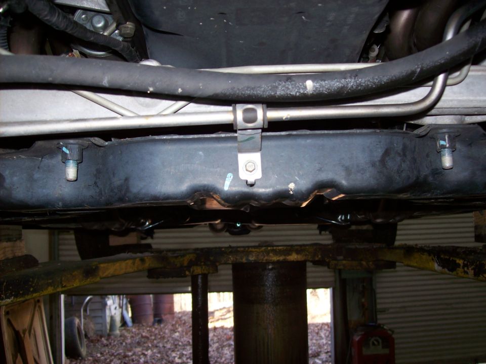 Underside view of vehicle frame with exhaust pipes and fuel lines visible