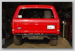 1986 Ford Bronco - Rear view of a red SUV, likely a Ford Bronco, in a garage setting.
