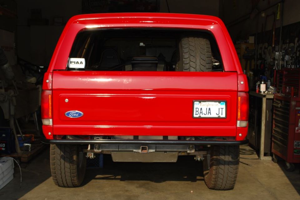 Rear of red Ford Bronco with California plate 'BAJA JT' in a garage