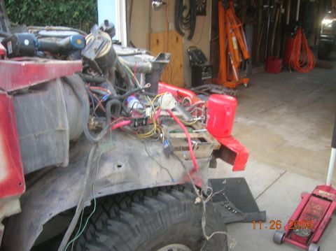 1985 Ford Bronco - Vehicle engine bay during a rebuild, showing extensive wiring and components. A red jerry can is mounted on the fender.
