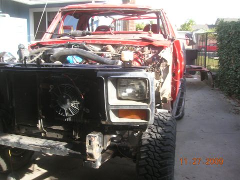 1985 Ford Bronco - This heavily modified red Ford Bronco shows significant damage and missing body panels, indicating it is undergoing extensive repairs or cu…