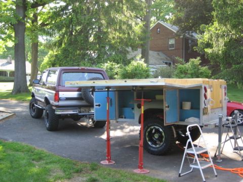 1996 Ford Bronco - Custom camper shell mounted on a trailer, parked behind a 1996 Ford Bronco.