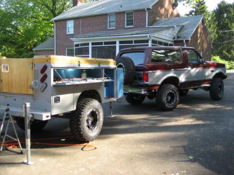 1996 Ford Bronco - A Ford Bronco is parked in a driveway next to a utility trailer with its doors open.