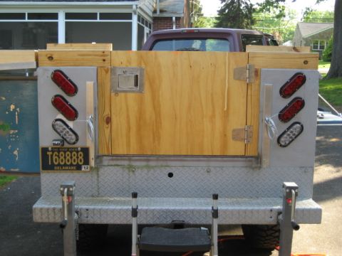1996 Ford Bronco - Rear view of a truck bed a custom wooden door and trailer lights, with a Delaware license plate visible.