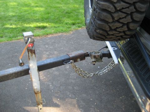 1996 Ford Bronco - A trailer hitch and safety chains are connected to the rear of a vehicle, with a spare tire visible.