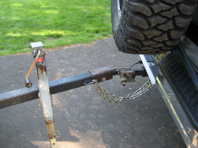 Trailer hitch with chains connected to a vehicle bumper, spare tire mounted on the rear